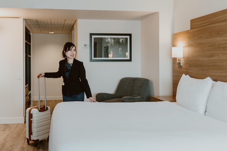 Woman holding luggage in hotel room