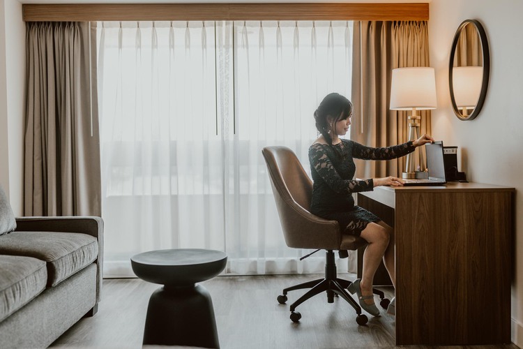 Women opening up laptop on desk in hotel room