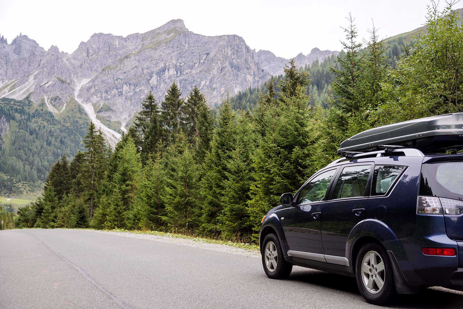 Car driving on a road surrounded by mountains and forests